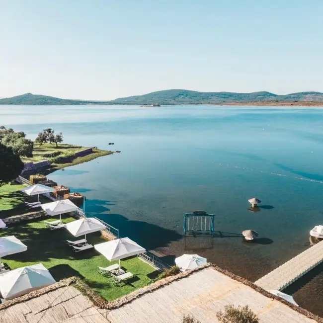 Cunda'da, denizin berrak sularına nazır, şemsiyelerle donatılmış çimenlik alanı, iskele ve su içi salıncaklarıyla sakin bir tatil cenneti sunan MŌLA Cunda Hotel & Beach'in kuşbakışı görüntüsü, Ayvalık rehberimizin huzurlu tatil önerilerinden birini gözler önüne seriyor.