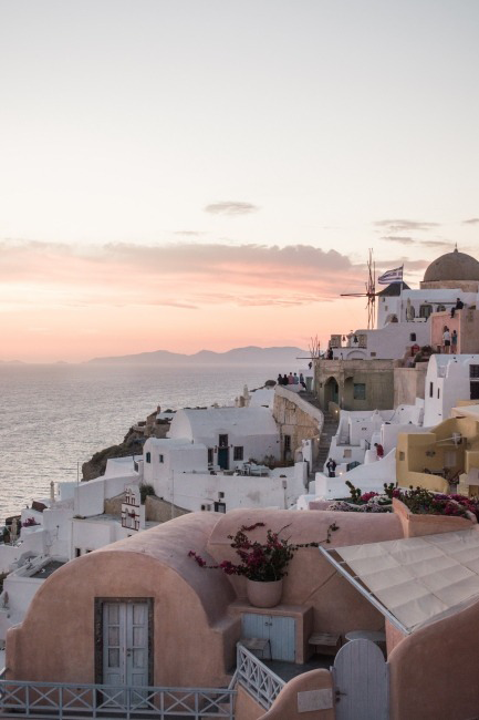 Yunanistan'ın göz alıcı adası Santorini'de, gün batımının pastel tonlarıyla aydınlanan, Ege Denizi'ne nazır bembeyaz geleneksel evlerin ve mağara evlerin yamaçlara sıralandığı, yel değirmeni ve Yunan bayrağının eşlik ettiği bu büyüleyici manzara, rüya gibi bir ev kiralama tatili vadediyor.