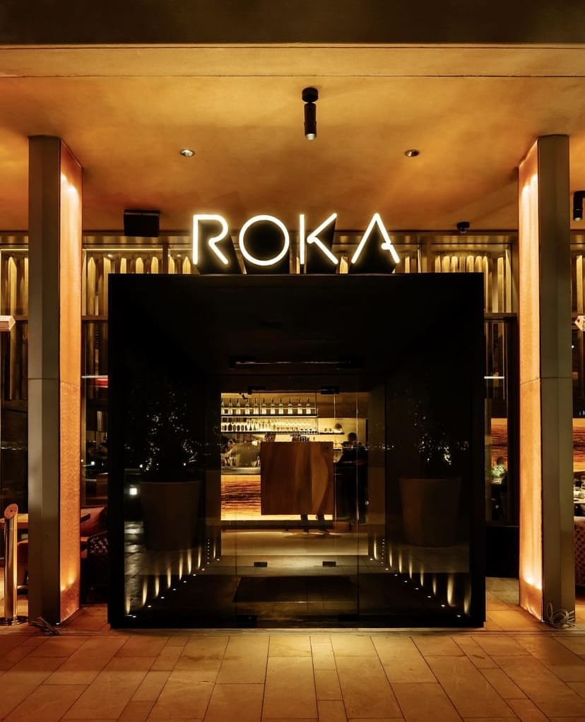 Gece, çağdaş Japon mutfağının sunulduğu Roka restoranının ışıklı neon tabelası altında, zarif bar alanı içeriden görünen cam bir girişten sızan sıcak ışıklarla aydınlatılmış, İstanbul'un en iyi teraslı mekanlarından birinin davetkar atmosferini sergiliyor.