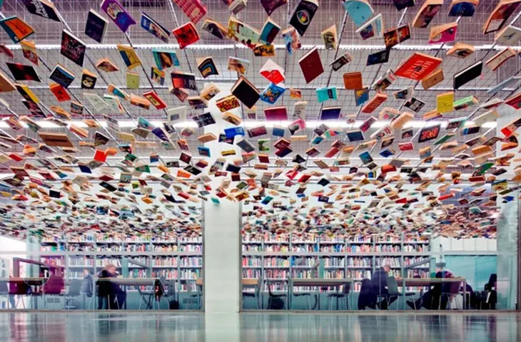 İstanbul Modern’in aydınlık kütüphane odasında raflarda kitaplar ve çalışma masalarının olduğu iç mekân görünümü.