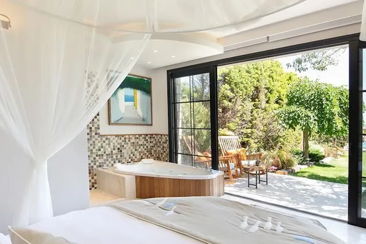 Bir cibinlikle süslenmiş büyük, beyaz bir yatağın ve jakuzili lüks bir otel odasının görüldüğü bu evcil hayvan dostu otel, sürgülü cam kapılarından yemyeşil bir bahçeye açılan özel bir veranda ile evcil dostunuzla keyifli anlar vadeden konforlu bir konaklama deneyimi sunuyor.