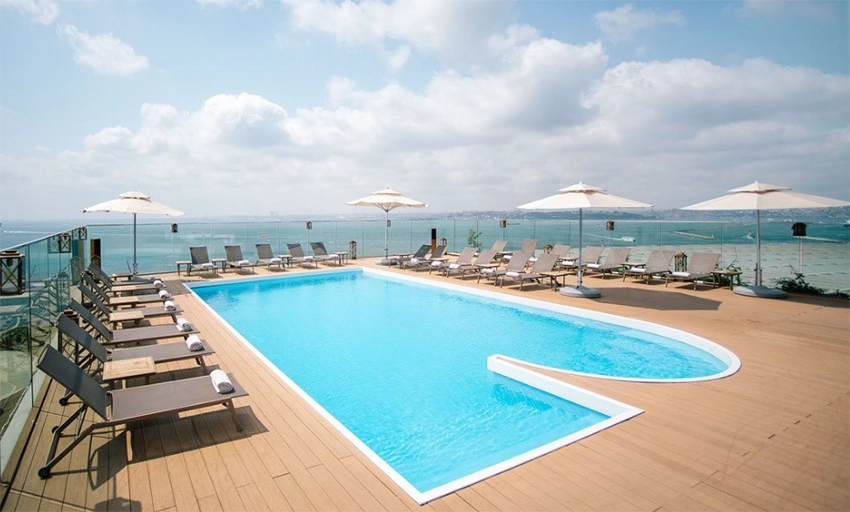 Moda'daki DoubleTree by Hilton Hotel'in ahşap zeminli terasında konumlanan, masmavi suyu ve şezlonglarıyla davetkar görünen otel havuzu, İstanbul'un en iyi otel havuzlarından biri olarak yaz kaçamağı sunan muhteşem bir manzaraya sahip.