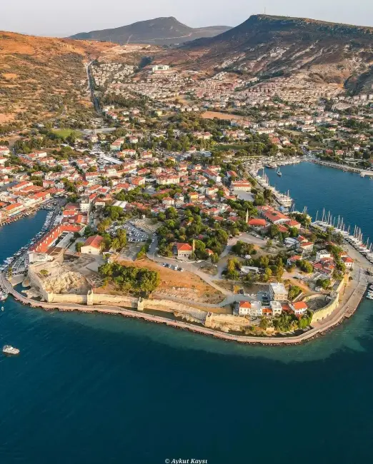 Kuşbakışı Foça'da, Ege Denizi kıyısına kurulmuş antik liman kentinin kendine özgü mimarisi, teknelerle dolu işlek marinası, tarihi surları ve yemyeşil tepelerle çevrili büyüleyici manzarası, tatil rotası arayanları cezbeden doğal ve kültürel zenginliğini vurguluyor.