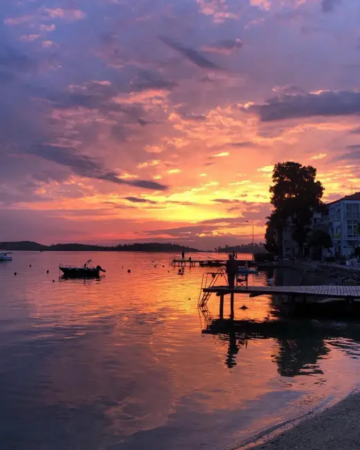 Ege'nin sevilen rotası Foça'da, mor, pembe, turuncu tonlarının suya yansıdığı göz kamaştırıcı bir gün batımında, iskelede duran bir siluet ve teknelerin oluşturduğu huzurlu ambiyans, tatil için ideal zamanları çağrıştırıyor.