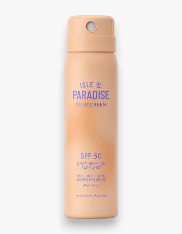 Açık şeftali renginde, üzerinde mor harflerle Isle of Paradise Sunscreen Daily Defence Face Mist yazan, SPF 50 yüksek korumalı bir güneş kremi ve makyaj üzerine kullanılabilen bir yüz spreyi şişesi.