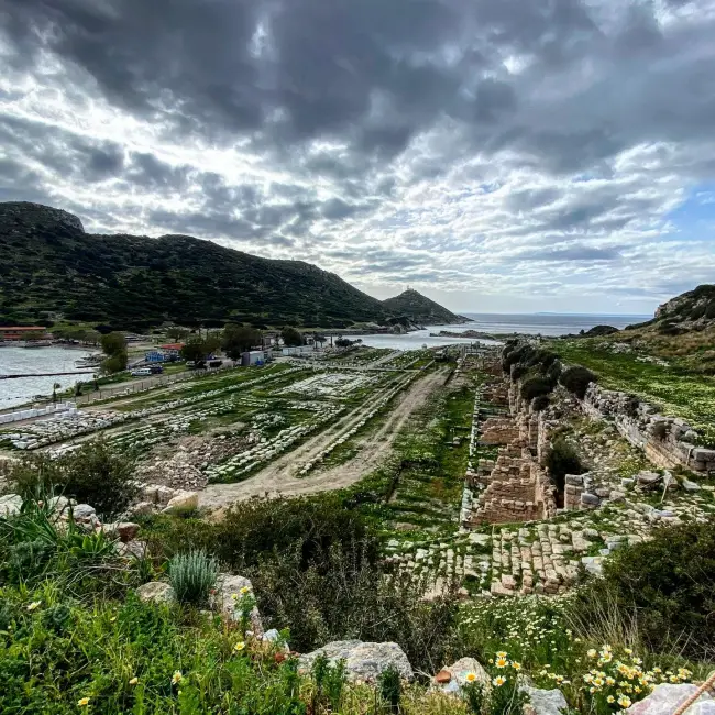 Datça Yarımadası'nın Ege ile Akdeniz'in birleşme noktasında yer alan Knidos Antik Kenti'nin yemyeşil çimlerle kaplı geniş kalıntıları, uzaklarda denize nazır yükselen bir tepedeki fenerle birlikte bulutlu bir gökyüzünün altında uzanarak tarihin dinginliğini yansıtıyor.