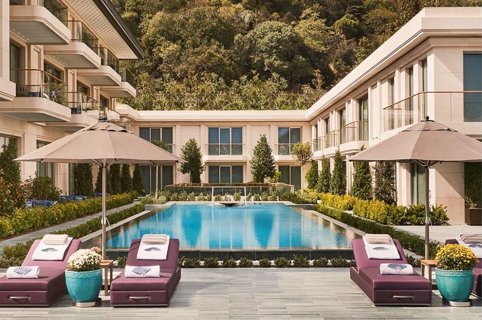 Mandarin Oriental Bosphorus İstanbul'un yemyeşil Naile Sultan Korusu ile çevrili lüks otel havuzu, mor şezlonglar, şemsiyeler ve saksı çiçekleriyle yaz kaçamağı arayanlara şehrin ortasında dinlendirici bir atmosfer sunuyor.