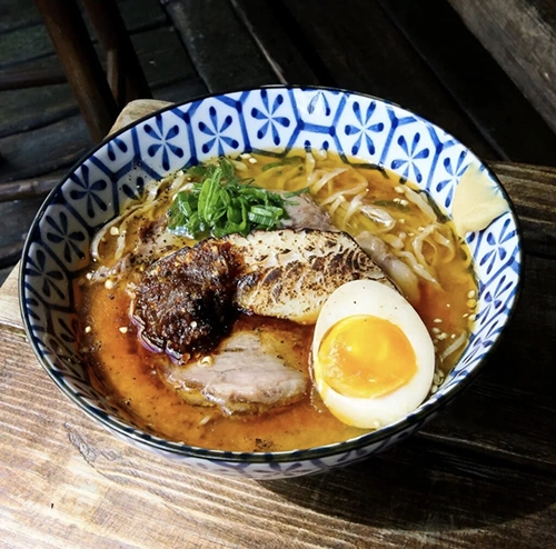 Paris'in en iyi restoranları listesinde adı geçen Kodawari Ramen'den, zengin kırmızımsı et suyunda bolca erişte, karamelize et dilimleri, ortası akışkan haşlanmış yumurta, taze yeşil soğanlar ve baharatlı sos ile geleneksel desenli bir kasede sunulan, adeta bir lezzet şöleni yaratan ramen tabağı.