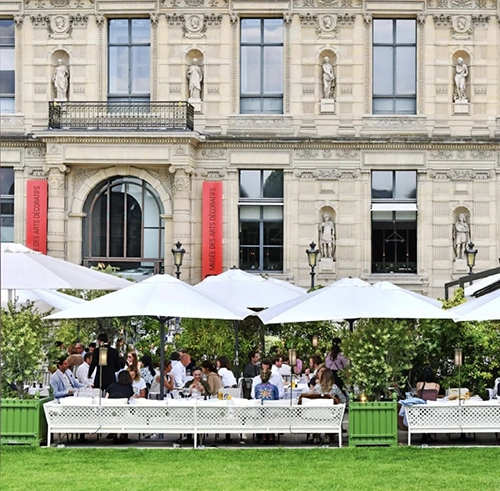 Musée des Arts Décoratifs’in görkemli taş cephesi önünde, beyaz şemsiyelerle gölgelenmiş yemyeşil bir bahçede, keyifle yemek yiyen kalabalık grupların bulunduğu Loulou, Paris’in Akdeniz esintili en iyi restoranlarından birinin hareketli ambiyansını yansıtıyor.