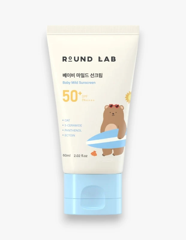 Üzerinde Round Lab markası, 베이비 마일드 선크림 (Baby Mild Sunscreen) yazısı ve sörf tahtası tutan kalp gözlüklü şirin bir ayıcık illüstrasyonu olan, SPF 50+ PA++++ koruması ve yulaf, 5-seramid, panthenol, ektoin gibi bileşenleri listeleyen 60 ml'lik açık mavi kapaklı beyaz tüp bebek güneş kremi.