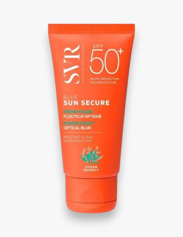 Beyaz arka planda duran, parlak turuncu renkli SVR Sun Secure Crème Mousse Optical Blur SPF 50+ güneş koruyucu tüpü; yüksek koruma, suya dayanıklılık ve cilde optik bulanıklık etkisi sunarken, Ocean Respect logosuyla çevreye duyarlılığını sergiliyor.