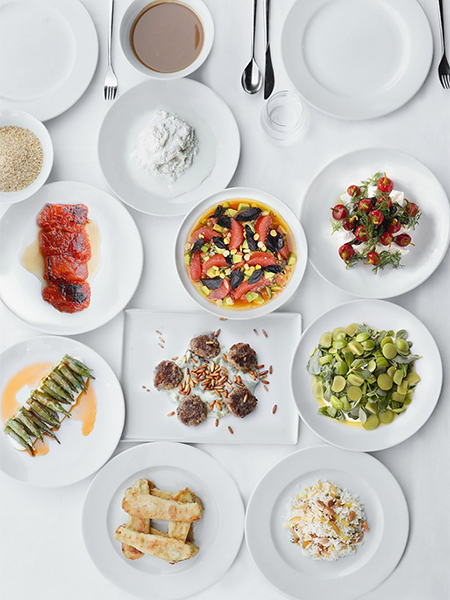 Antalya'daki en iyi restoranlardan birinde, geleneksel Türk ve modern Akdeniz mutfağının en lezzetli örneklerinden olan çam fıstıklı köfteler, taze sebzeli ve meyveli salatalar, pilav ve zengin meze çeşitleriyle bezenmiş beyaz bir masa kuşbakışı açıyla görülüyor.