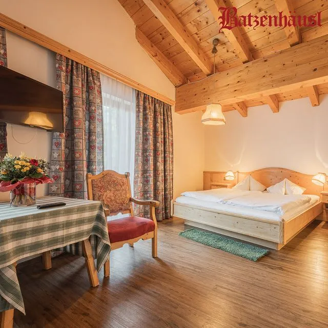 Avusturya'nın Seefeld in Tirol bölgesinde yer alan Gasthof Batzenhäusl'daki bu davetkar balayı oteli odası, ahşap kirişli tavanı, rustik ahşap zemini, kalpli desenli perdeleri, geleneksel mobilyaları ve yeşil ekoseli masa örtüsüyle kültürel dokuyu koruyan sıcacık bir balayı atmosferi sunuyor.