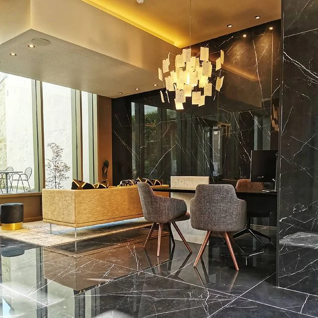 Bu modern ve şık otel lobisinde, koyu mermer zeminlerin ve duvarların yansıttığı çağdaş bir atmosferde, özgün tasarımlı avize ışığı altında konumlanan konforlu oturma grubu ve geniş cam pencerelerle dış mekana açılan ferah bir ortam, balayı rotaları içinde lüks ve huzurlu bir konaklama deneyimi vadediyor.