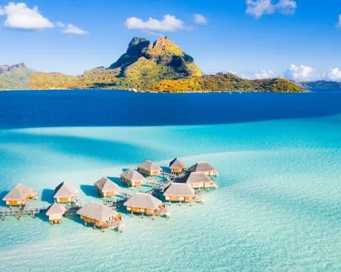 Bora Bora'nın kristal berraklığındaki turkuaz suları üzerinde uzanan, hasır çatılı çok sayıda lüks su üstü villası, romantik balayı rotaları arasında nefes kesici bir seçenek sunarken, arka planda yükselen yemyeşil Otemanu Dağı manzarayı adeta bir tablo gibi tamamlıyor.