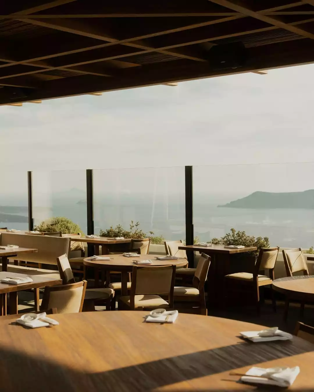 Nobu restoranının şık yarı açık yemek alanında, açık renk ahşap masalar ve sandalyeler deniz ve uzak adaların nefes kesen panoramik manzarasına karşı konumlanmış, misafirlerini huzurlu bir yemek deneyimine davet ediyor.