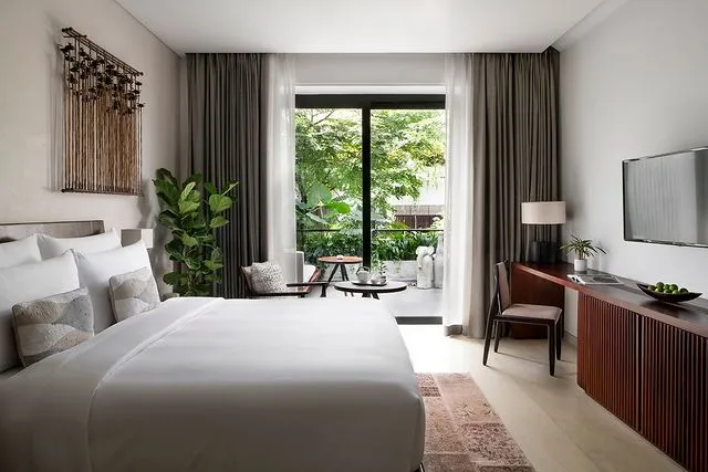 Treeline Urban Resort'un beyaz nevresimli rahat yatağı, duvardaki sanatsal dekorasyonu, özel balkonundan Siem Reap'in yemyeşil doğasına açılan penceresi ve modern detaylarıyla bu oda, kültür ve doğa tutkunu balayı çiftleri için huzurlu ve estetik bir konaklama alternatifi sunuyor.
