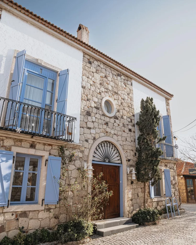 Kurabiye Otel'in geleneksel mimarisini yansıtan, alt katı taş, üst katı beyaz sıvalı cephesiyle iki katlı bir bina, mavi panjurlu pencereleri, demir korkuluklu balkonu ve kemerli ahşap kapısı önündeki kaldırım taşlarıyla dikkat çekiyor.