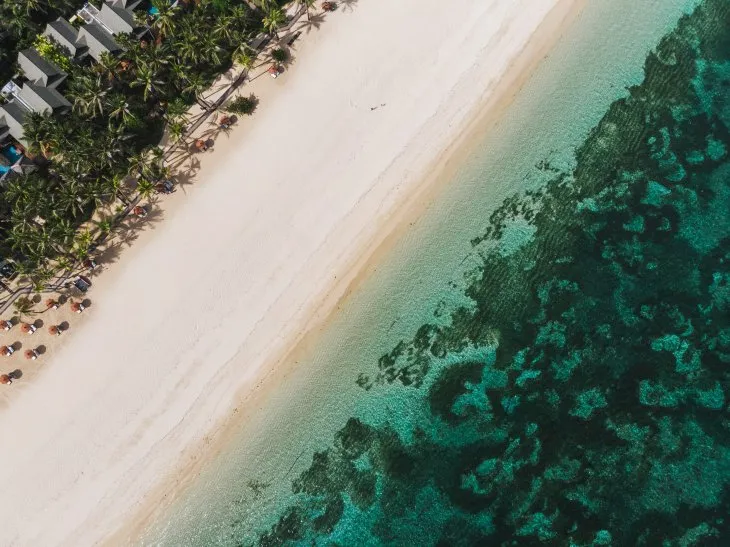 Bali’deki Nusa Dua plajında beyaz kumlar, turkuaz deniz ve sahil boyunca uzanan lüks otellerin havadan görünümü