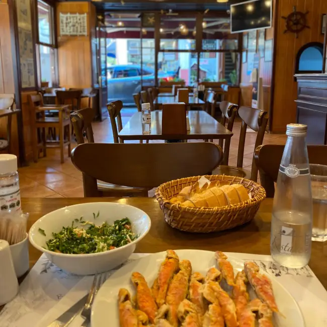 Arnavutköy’ün ünlü alkolsüz balıkçısı Adem Baba’da servis edilen balık çorbası ve taze mezelerle sade bir iç mekân atmosferi.