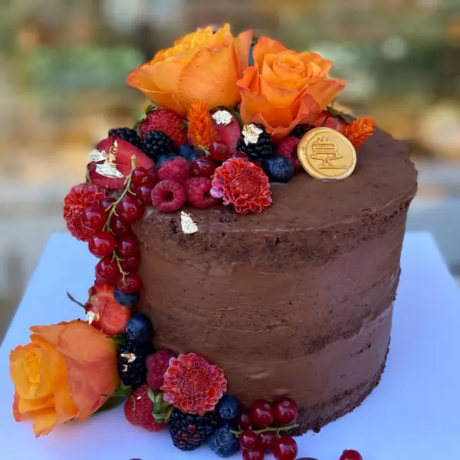 Arnavutköy’deki Cutie Cake pastanesinde çikolatalı kat kat pasta; taze meyveler, yenilebilir altın yapraklar ve turuncu güllerle zarif şekilde süslenmiş.