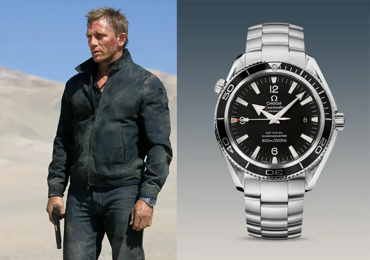 Çorak bir arazide elinde tabanca, yüzünde yara izleri ve kolunda bir saatle Daniel Craig'in canlandırdığı James Bond karakteri ile sağda detaylı bir şekilde gösterilen gümüş renkli, siyah kadranlı Omega Seamaster Planet Ocean saati, James Bond'un vazgeçilmez saatleri koleksiyonundan birini vurguluyor.