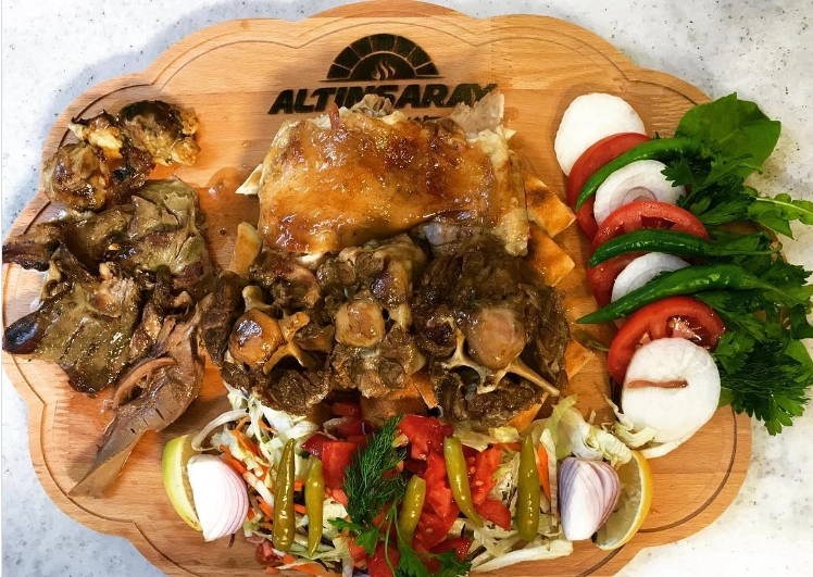 Altınsaray logosu taşıyan ahşap servis tahtasında, odun ateşinde uzun süre pişirilmiş, kemikli pöç tandır etleri ile birlikte nar gibi kızarmış diğer et parçaları, taze salata ve kırmızı soğan dilimleriyle süslenmiş bu yöresel Kayseri lezzeti iştah kabartıyor.