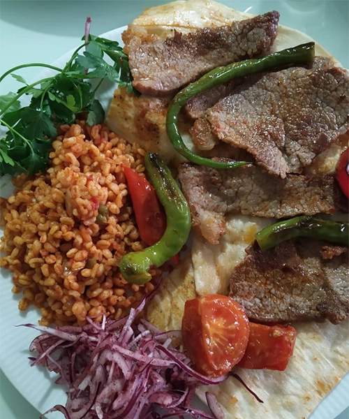 Kayseri'nin en beğenilen restoranları arasında yer alan Kebapçı Şakir'in usulüne göre sacda kendi yağında pişirilmiş, lavaş üzerinde servis edilen nefis et dilimleri, közlenmiş yeşil ve kırmızı biberler, yanında bulgur pilavı, sumaklı soğan salatası ve domatesle sunulan doyurucu bir kebap tabağı.