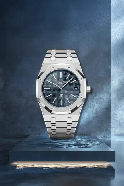 Şık bir podyum üzerinde sergilenen, sekizgen bezelli ve Audemars Piguet imzalı Petite Tapisserie desenli lacivert kadranıyla denizin derinliklerinden rengini alan paslanmaz çelik bir Audemars Piguet Royal Oak Jumbo Extra Thin saat.