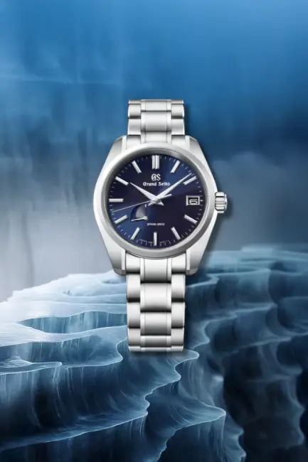 Grand Seiko Spring Drive SBGA375 lacivert saat modeli, buzlu deniz dalgalarını andıran koyu mavi bir arka plan üzerinde dikkat çekiyor; parlak paslanmaz çelik kasası ve bileziği, denizin derinliklerinden ilham alan koyu mavi kadranıyla şıklığı ve zarafeti yansıtıyor.