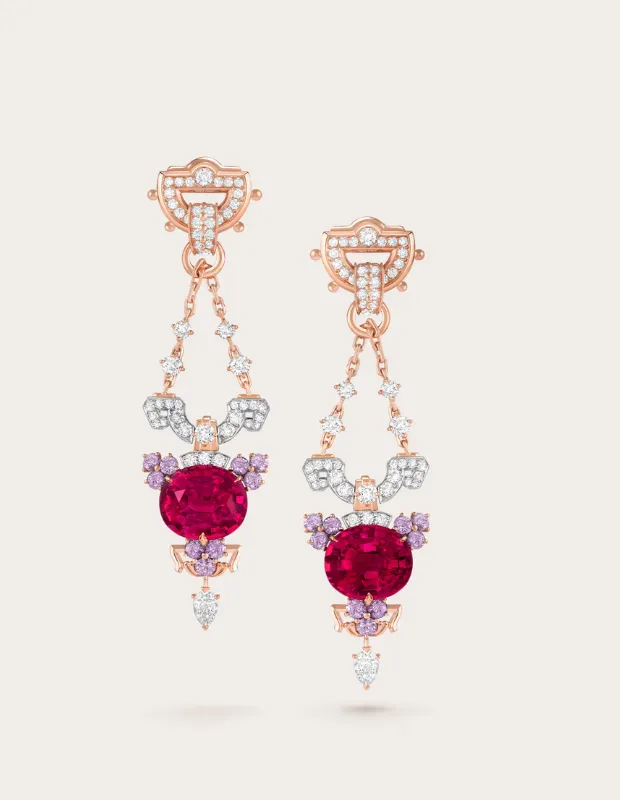 Pembe oval kesim taş merkezli, etrafı pırlanta ve lila tonlu taşlarla çevrili; rose altın montürlü, sarkıtlı ve detaylı tasarıma sahip yüksek mücevher küpe çifti.