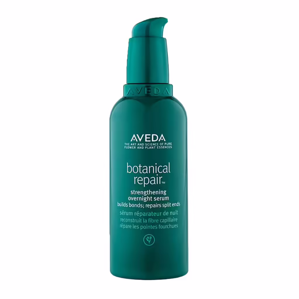 Parlak beyaz bir zeminde dikey olarak konumlandırılmış, teal-yeşili bir pompa başlıklı şişe, AVEDA botanical repair güçlendirici gece serumunu vurgulayarak kuru saçlar için onarım ve nem sağlamanın önemini gösteriyor.