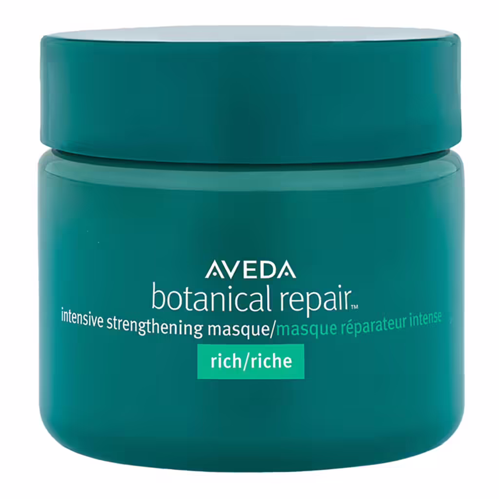 Koyu teal renkli kapaklı, üzerinde Aveda Botanical Repair Intensive Strengthening Masque ve 'rich' yazan bir kavanoz saç maskesi, kuru saçlara derinlemesine nem sağlamak ve onarım sunmak için etkili bir nem rutini parçası olarak sunuluyor.
