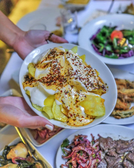 Küçük Kulüp Meyhane Teşvikiye’de yoğurt ve sos eşliğinde servis edilen çıtır patates meze tabağı