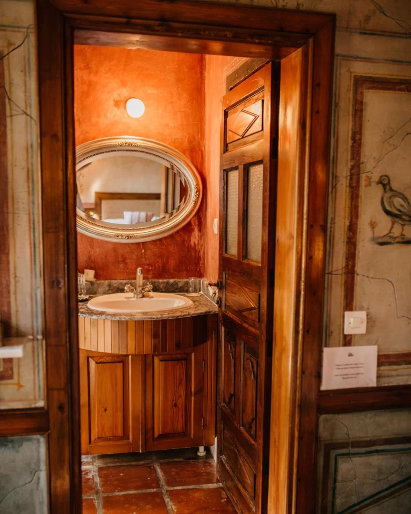 Nişanyan Hotel’de geleneksel ahşap kapılı banyo, mermer lavabo ve oval ayna detayları