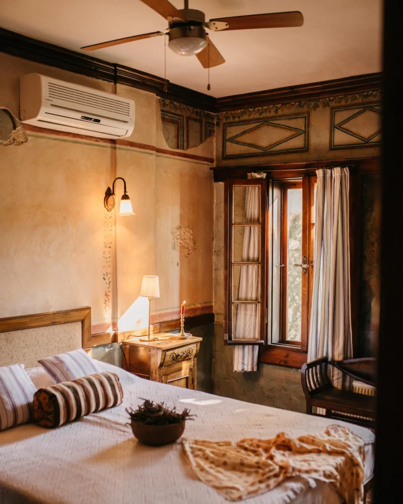 Nişanyan Hotel’in tarihi atmosferini yansıtan otantik yatak odası, ahşap pencere ve klasik dekorasyonuyla huzurlu bir konaklama alanı