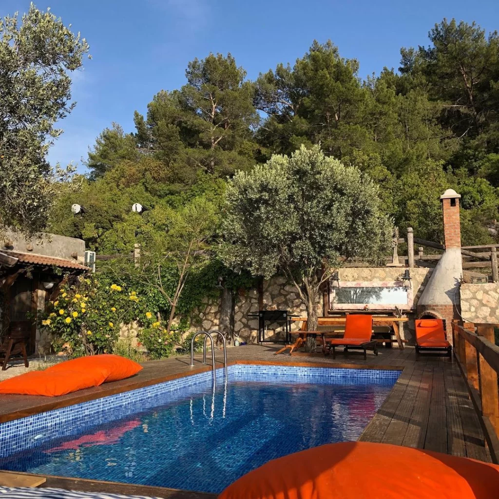 Prima Donna Hotel Kalkan Patara’da ağaçlarla çevrili özel havuzlu villa ve şezlonglarla dinlenme alanı