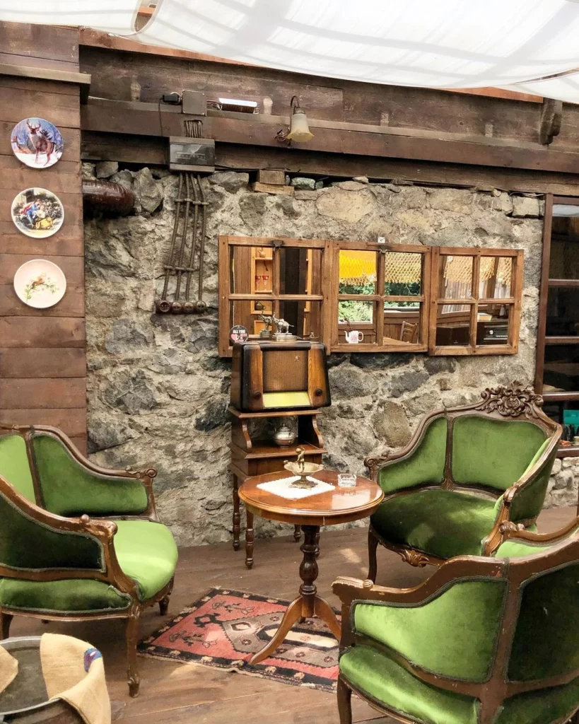 Puli Mini’nin nostaljik köşesi: taş duvarlı, vintage yeşil koltuklar ve eski radyoyla sıcak bir oturma alanı.