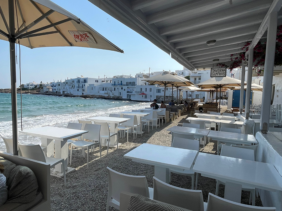 Paros adasında yer alan, bembeyaz masa ve sandalyelerin sahile dizildiği, denizin hemen kenarındaki ünlü Glafkos Taverna'nın, arka planda geleneksel Kiklad evlerinin sıralandığı Naousa koyundaki huzurlu atmosferi.