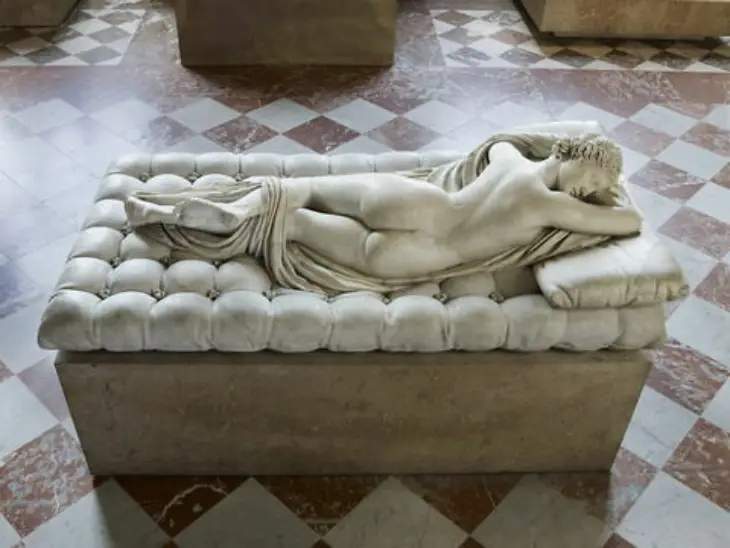 Louvre Müzesi'nin önemli eserlerinden biri olan bu detaylı mermer heykel, tufted bir bank üzerinde yüzükoyun yatan, bedeni hafifçe örtülmüş, huzurlu bir şekilde uyuyan genç bir figürü sanatsal bir incelikle gözler önüne seriyor.