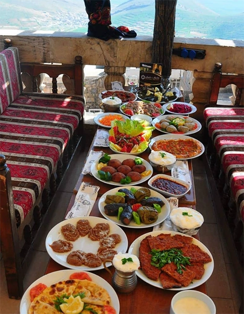 Geleneksel desenli minderlerle süslü sedirlerin çevrelediği, içli köfte, zeytinyağlı dolmalar, lahmacun benzeri hamur işleri, bol salata ve yöresel tatlılarla donatılmış uzun bir masada, Mezopotamya ovasına nazır keyifli bir ziyafet sofrası uzanıyor, güneşli havada enfes lezzetler sunuyor.
