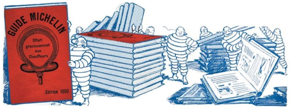 Bibendum maskotunun ilk Michelin Rehberi’nin kırmızı baskısıyla birlikte çizildiği vintage illüstrasyon; rehberin tarihini ve karakterin simgesel önemini yansıtıyor.