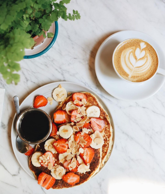 Çilek ve muz dilimleriyle süslenmiş pancake tabağı ve latte, Moda’da Anadolu Yakası’nın en iyi kahvecilerinden Story Coffee’de