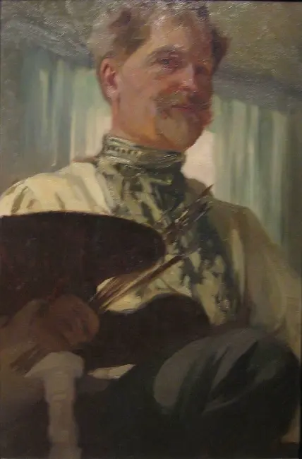 Fırçaları ve paletiyle resmedilen Alphonse Mucha portresi, sanatçının atölyesinde yaratım anını yansıtan yağlı boya tablo.