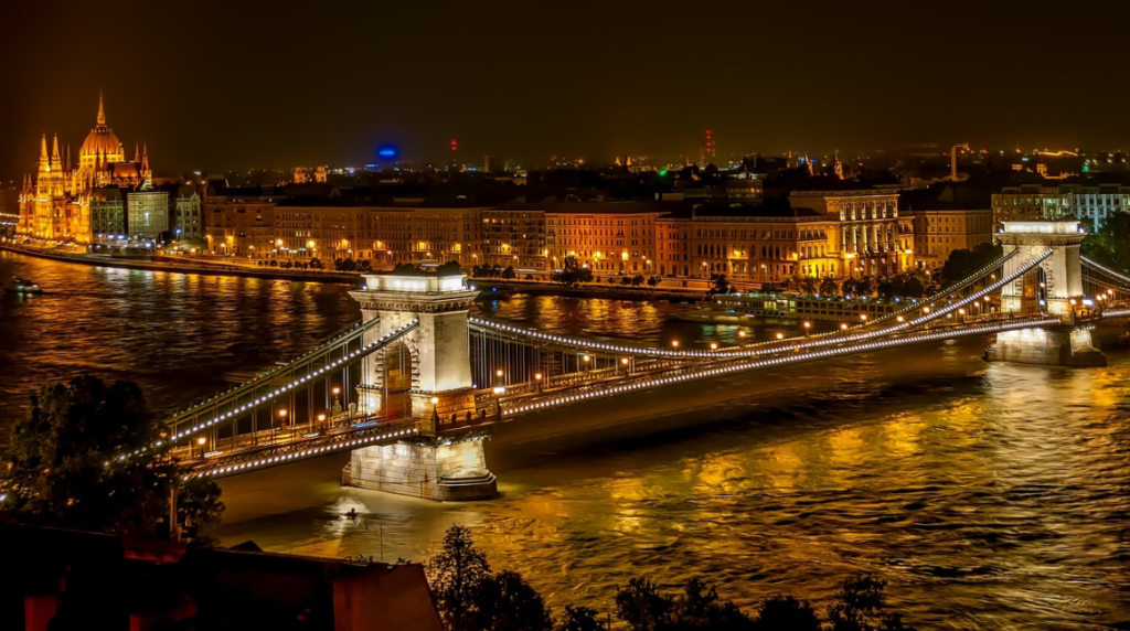 Budapeşte'nin büyüleyici gece manzarasında, Tuna Nehri üzerinde pırıl pırıl ışıklarla süslenmiş tarihi Zincirli Köprü ile nehrin sol kıyısında tüm ihtişamıyla aydınlatılmış Parlamento Binası, şehrin eşsiz güzelliğini gözler önüne seriyor.