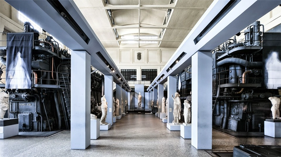 Roma Seyahat Rehberi içeriğindeki Centrale Montemartini Müzesi'nin bu etkileyici görseli, eski bir elektrik santralinin devasa endüstriyel makineleri arasında zarifçe sergilenen Antik Roma heykellerinin yarattığı benzersiz ve büyüleyici kontrastı sergiliyor.