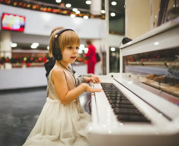 Kulaklık eşliğinde interaktif müzik uygulamaları ve piyano eğitimi ile nota öğrenen çocuk.