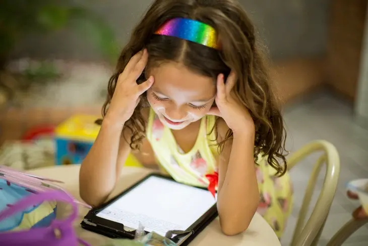 Tablet ekranındaki eğlenceli ve öğretici içeriklerle interaktif bir şekilde öğrenen gülümseyen çocuk.