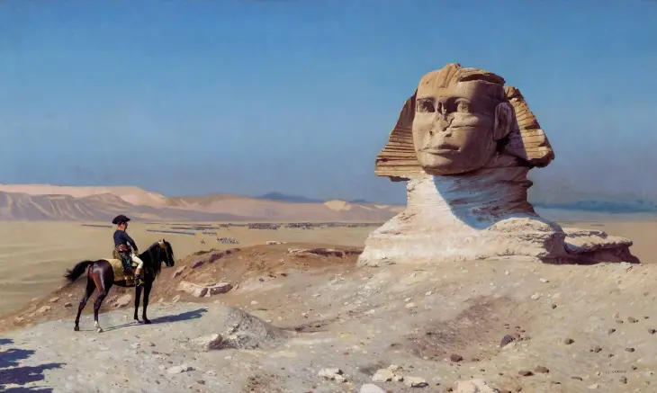 Mısır çölünün genişliğinde, Büyük Gize Sfenksi'nin heybetli görüntüsüne bakan, askeri üniformalı Napoleon Bonaparte'ın at sırtında tasvir edildiği bir tablo, arka planda uzanan kum tepeleri ve uzaktaki askeri birlikler ile Napoleon'un hayatındaki Mısır seferini yansıtan detaylar sunuyor.