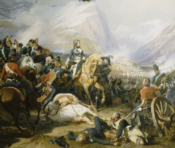 Karlı dağların çevrelediği savaş alanında, askeri üniformasıyla açık renk atının üzerinde duran Napoleon Bonaparte, etrafında atlar ve yaralı askerlerle dolu yoğun bir çatışmayı gözlemlerken, ilerideki orduların çarpıştığı anı yansıtan tarihi bir tablo.